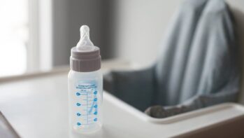 ベビーチェアのトレイに置かれた哺乳瓶（赤ちゃんのミルク記事のアイキャッチ）