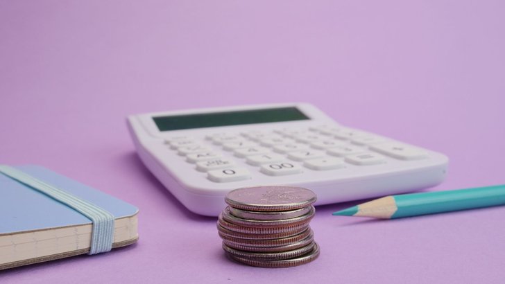 電卓と硬貨、文房具を並べた机