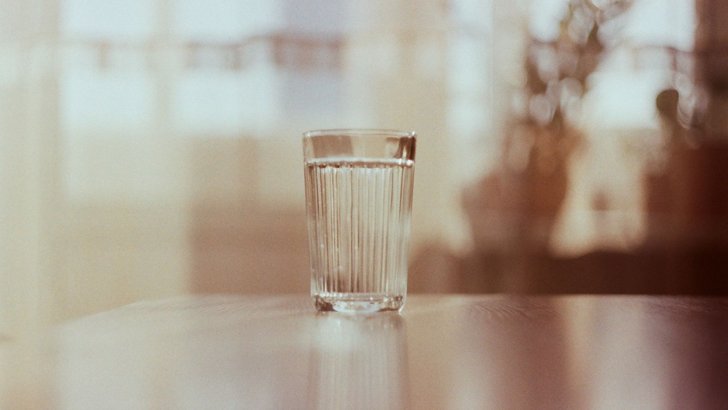 明るい室内のテーブルに置かれた水のグラス