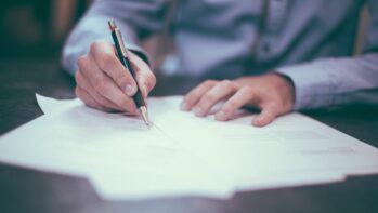 書類にペンで署名する手元（解約金一覧記事のアイキャッチ）