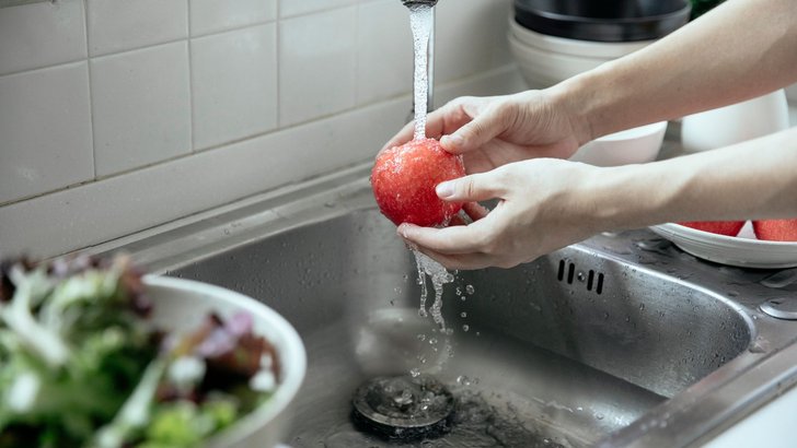 キッチンの流水でりんごを洗っているところ