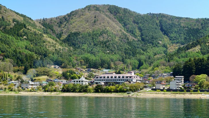 河口湖の湖面ごしに見える対岸の集落と、その背後の山