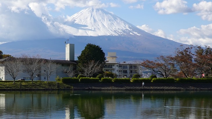 御殿場市東山の東山湖。湖の向こうに雪をかぶった富士山がそびえ、湖面に岸の木々と雲が映る